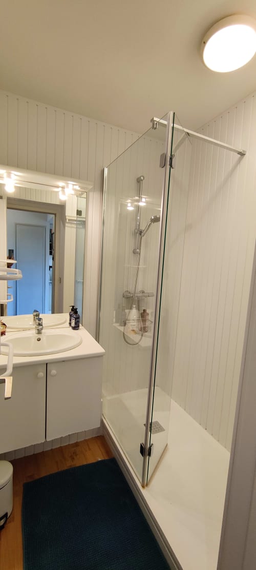 Salle de bain moderne chez Mer et Maisons avec douche vitrée, vasque blanche et murs carrelés verticaux