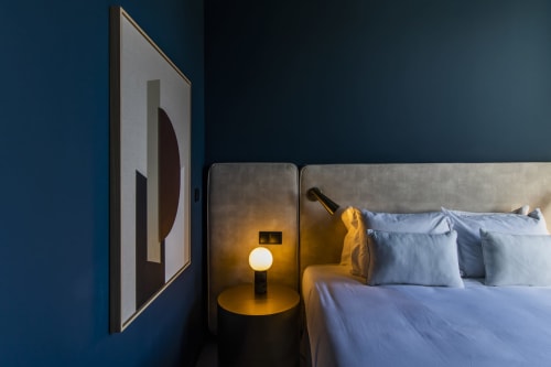 Quarto moderno do hotel Benefit Collection Porto com parede azul, luminária de cabeceira acesa e cabeceira estofada cinza