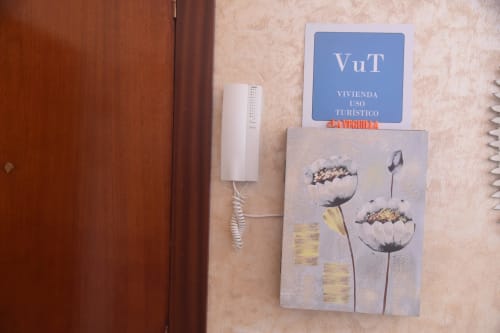 VUT tourist apartment sign on beige wall with intercom and decorative flower artwork in Benavente