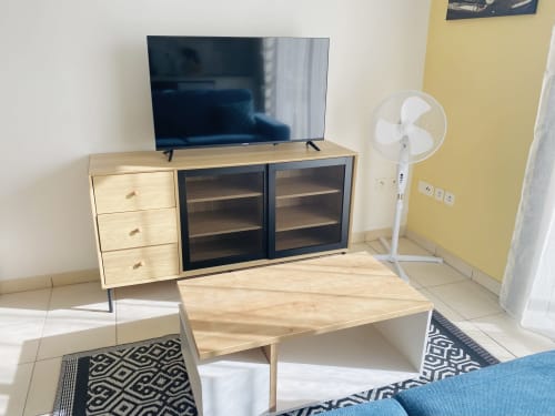Salon moderne à Sinnamary avec meuble TV en bois, télévision écran plat, ventilateur de plafond et tapis géométriques chez Maisons En