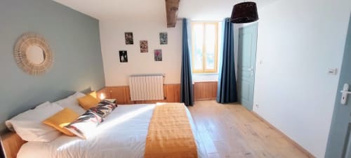 Bright bedroom in Orchids cottage at Les Gites de Campardon with queen bed, wooden floor, blue accents and garden view window