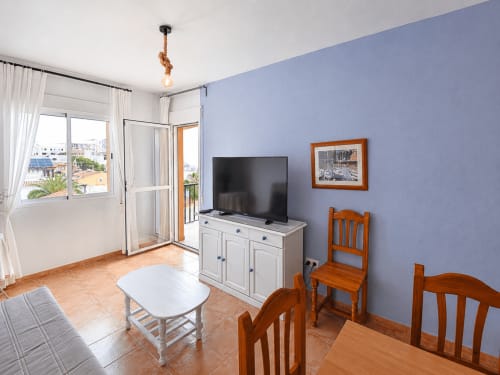 Bright apartment living room with TV, dining table, wooden chairs, and blue walls overlooking sea in Cuevas del Almanzora