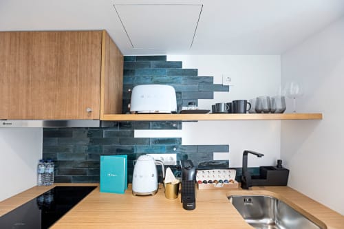 Kitchenette moderna em studio de hotel no Porto com balcões de madeira, backsplash de azulejos escuros, pia de aço inoxidável e eletrodomésticos