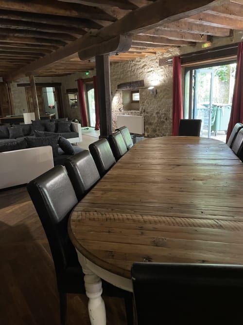 Coin repas avec table en bois et chaises en cuir noir dans le gîte rustique Les Pratges, Figeac