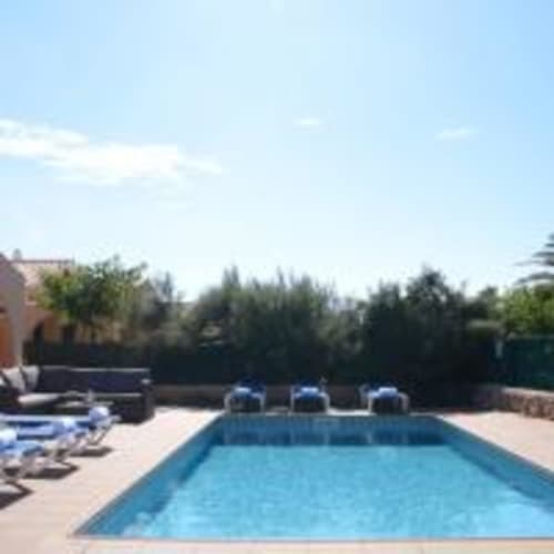 Piscina reluciente en la villa Las Golondrinas de Cap d'Artrutx con tumbonas, terraza y vistas arboladas