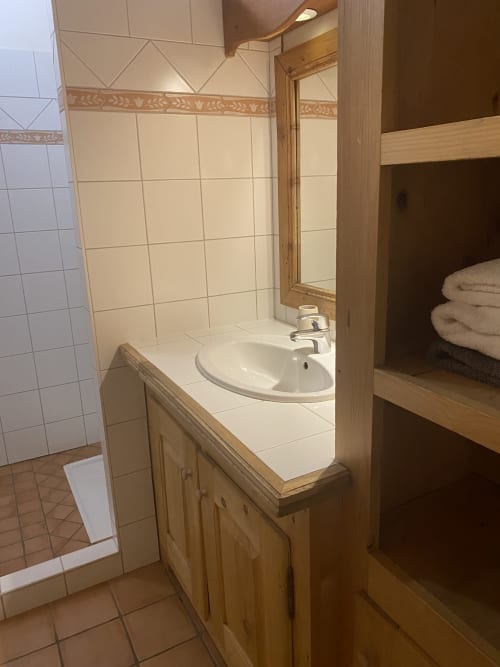 Salle de bain avec meuble vasque en bois, lavabo rond et murs carrelés blanc à l'appartement Vorès de La Ferme des Georgières