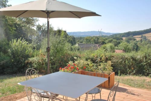 Terrasse de repas en plein air au Château de Vaux Morvan avec table, parasol et vue sur la campagne près d'Étang sur Arroux