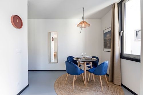 Área de refeições moderna em hotel do Porto com cadeiras azuis, mesa de madeira e luminária suspensa