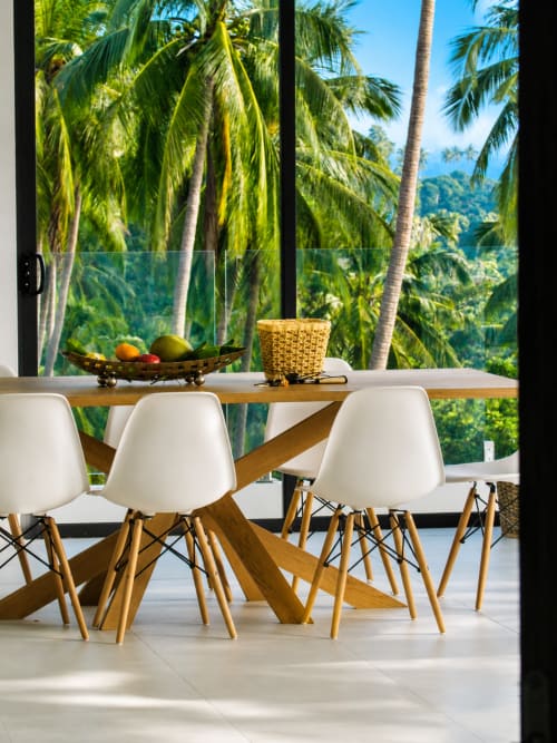 Modern dining area with white chairs at wooden table overlooking palm trees and mountains at Indigo Villa Samui, Ko Samui