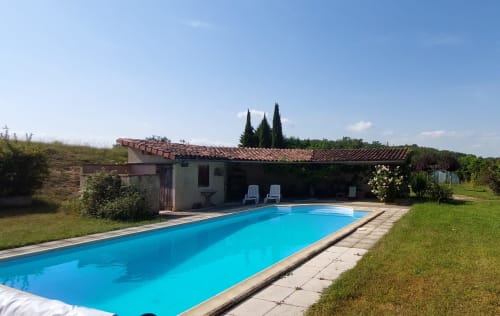 Rectangular swimming pool with turquoise water beside stone cottage at Les Gites de Campardon, Monties, with cypress trees