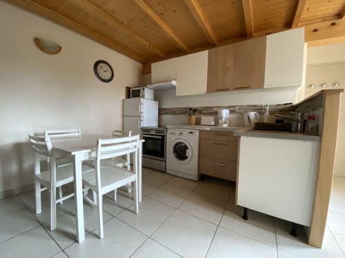 Cuisine moderne du gîte Le Cocon De Curson avec table blanche, plafond en bois et appareils en acier inoxydable