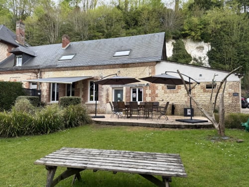 Les Gites De Flaubert cottage garden view with patio, umbrellas, and wooden picnic table in Le Héron, France