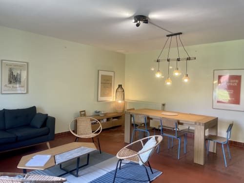 Intérieur de cottage moderne au Château de Vaux Morvan avec table à manger, chaises bleues, luminaires suspendus et vue sur le jardin
