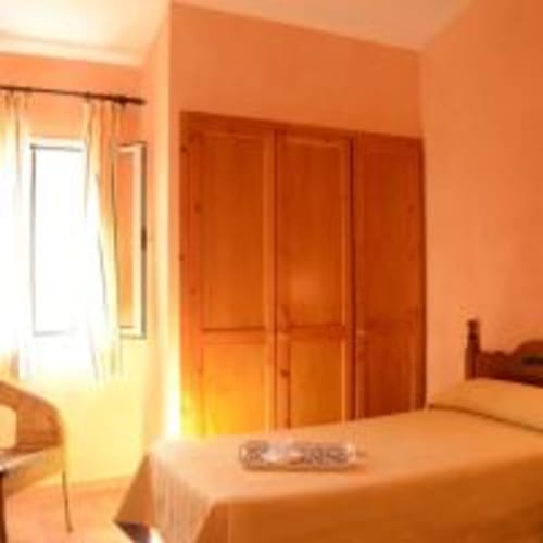 Dormitorio luminoso en villa Las Golondrinas, Cap d'Artrutx, con paredes naranjas, armario de madera y cama confortable