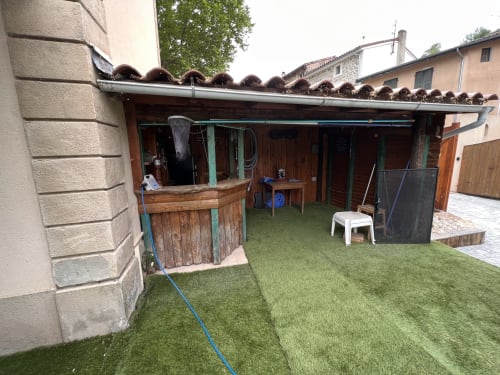 Cour rustique du Restaurant du Port à Saint-Pierre-de-Bœuf, avec structures en bois et pelouse verdoyante
