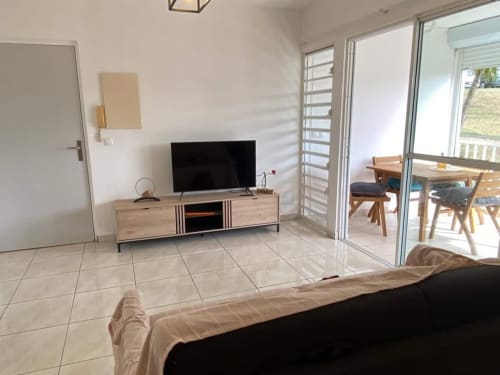 Appartement moderne Kay Betty avec TV, salle à manger et accès à la vue sur jardin par portes vitrées aux Trois-Îlets