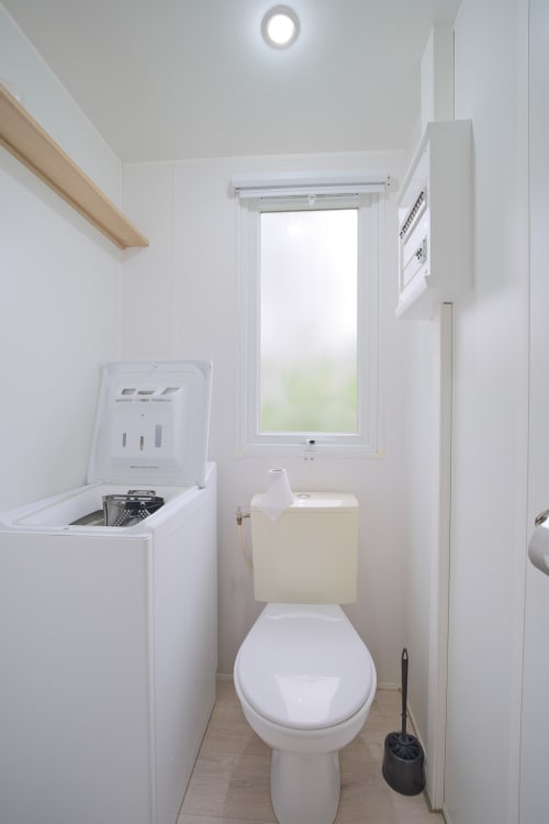 Salle de bain propre avec toilettes, lavabo, lave-linge et fenêtre à Annick Mobilhome à Vias Plage, France