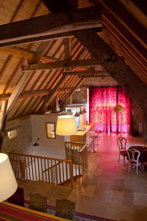 Intérieur du gîte Chambres d'hôtes Les Pratges à Figeac : poutres apparentes, rideaux rouges, lampes modernes et rampes en bois