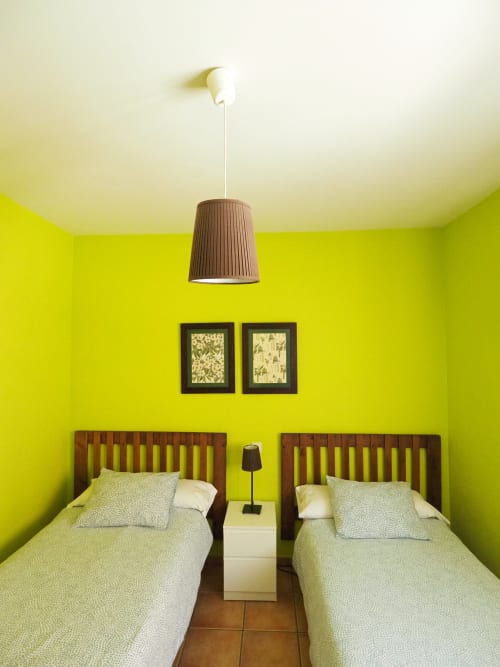 Luminoso dormitorio doble con camas de madera, lámpara colgante y cuadros en Rural Senda del Duratón