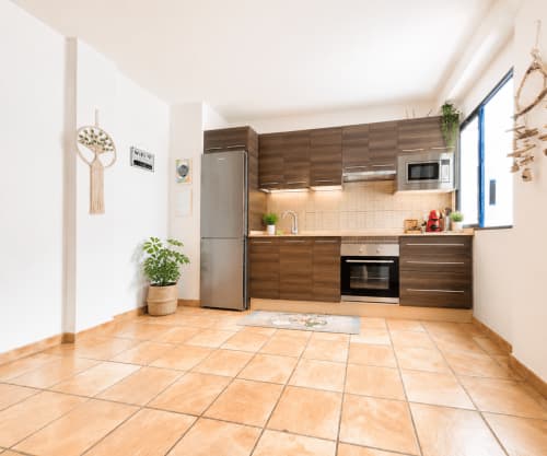 Cuisine moderne avec armoires en bois, appareils en acier inoxydable et carrelage en terre cuite à Corralejo