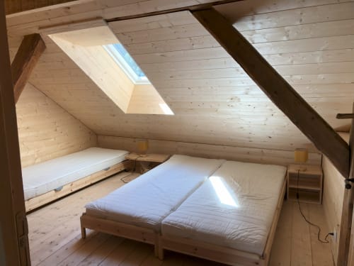 Bright attic bedroom at Les Chalets de l'Eau Rousse with two beds, skylight, wooden beams, mountain views