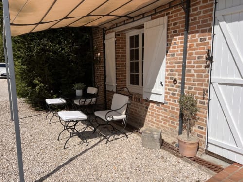 Espace de détente ombragé du Pigeonnier de la Farge à Chaumont-sur-Tharonne, avec bâtisse en brique et vue sur le jardin