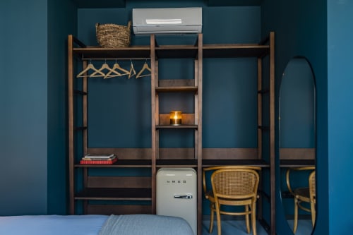 Studio de hotel no Porto com prateleiras de madeira, geladeira SMEG, cadeiras de madeira curvada, ar condicionado e paredes verde-azulado
