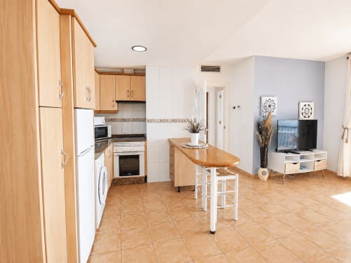 Open-plan kitchen and living area of Apartamentos El Calón Playa with wooden cabinetry, breakfast bar, and sea view apartment