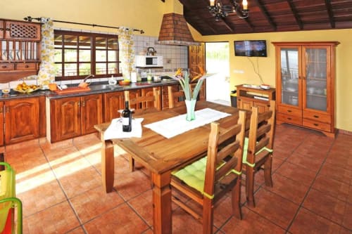 Amplia cocina y comedor de villa con muebles de madera, paredes amarillas y vistas a la montaña en Tijarafe, La Palma