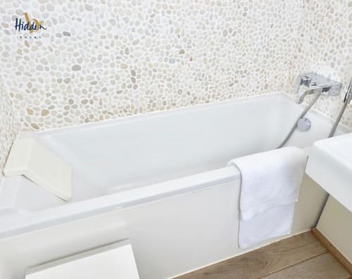 Modern bathtub with white towel in Hidden Bay Hotel Superior Room bathroom with pebble tile backsplash