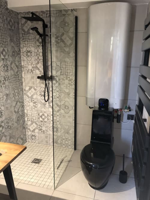 Salle de bain moderne du gîte ART DE VOYAGER à Étretat, avec douche à l'italienne, sèche-serviettes chauffant et accessoires noirs