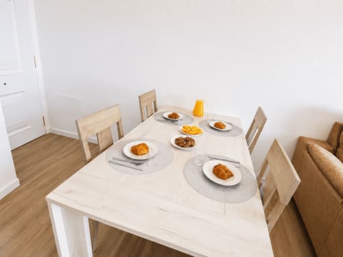Dining table set for breakfast at Apartamentos El Calón Playa with croissants, orange juice, and place settings