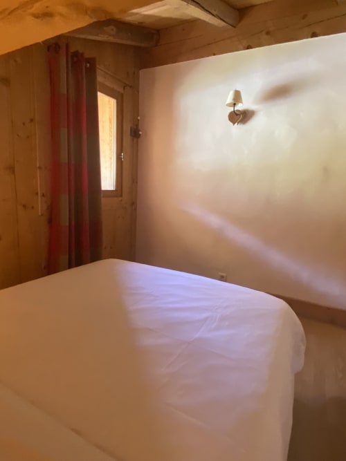Chambre douillette de l'appartement Vorès à La Ferme des Georgières, Notre-Dame-de-Bellecombe, avec lit, rideaux rouges et boiseries