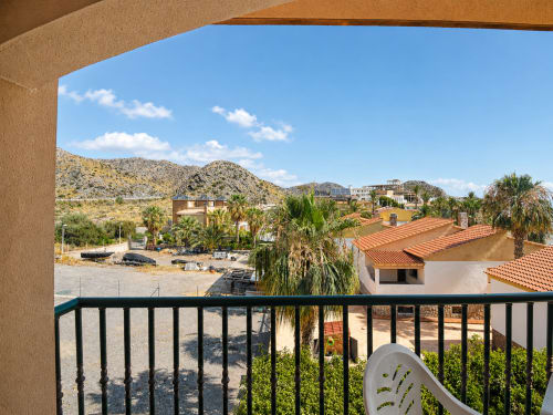 Balcony view from Apartamentos El Calón Playa in Cuevas del Almanzora with palm trees, arid hills, and Mediterranean