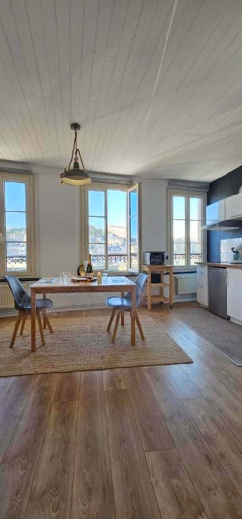 Salle à manger moderne avec vue sur mer, parquet, luminaire suspendu et cuisine à Saint-Valéry-en-Caux
