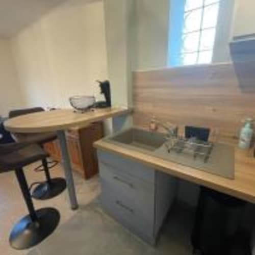 Espace de travail moderne dans un appartement à Perpignan avec bureau, écran, kitchenette, parquet et vue sur la ville