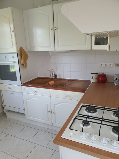 Cuisine moderne avec armoires blanches, plans de travail en bois, cuisinière à gaz et évier à l'appartement Hotel Cheverny La Vie Est Belle
