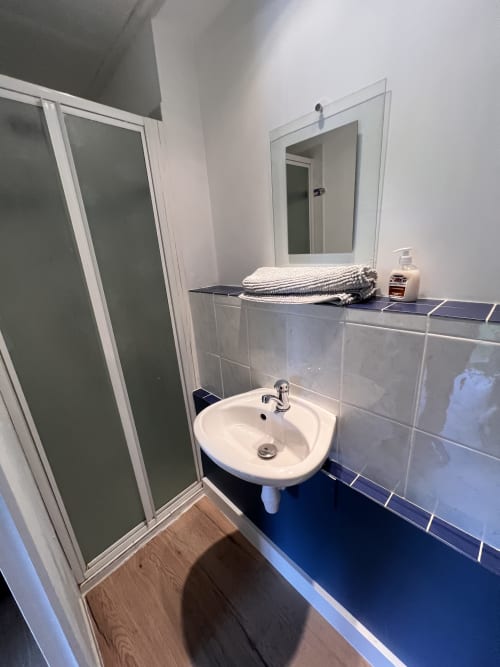 Salle de bain moderne du cottage Le Restaurant du Port avec lavabo, miroir, douche et carrelage bleu