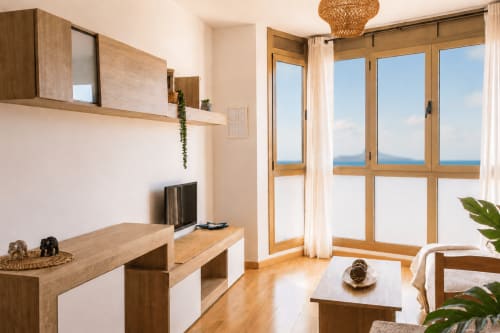 Appartement côtier moderne à Corralejo avec vue sur mer, mobilier en bois, séjour spacieux et grandes fenêtres donnant sur l'océan