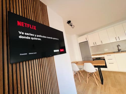 Pantalla de inicio de Netflix en televisor de pantalla plana en la sala-comedor moderna del apartamento de La Palma