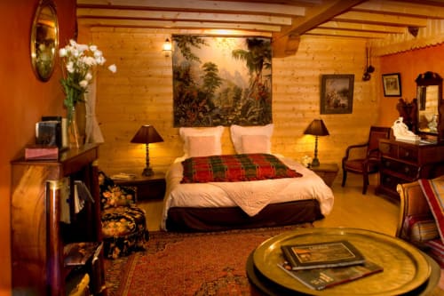 Chambre mauresque à l'Auberge Nemoz avec poutres en bois, table en laiton, art tropical et literie écossaise rouge au Haut-Bréda