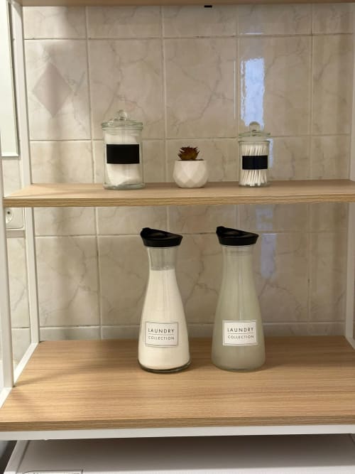 Étagère de salle de bain avec les bouteilles de la Laundry Collection et des pots décoratifsà l'appartement Le Paradis Des Logis à Pierrefitte