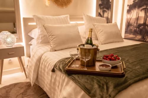 Chambre élégante au Domaine Valenquercy avec champagne, fraises fraîches et verres de vin sur plateau de lit