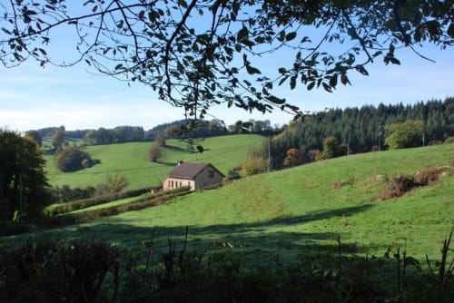 Maison en pierre dans les collines verdoyantes d'Étang sur Arroux, région du Morvan, France, avec forêt en arrière-plan