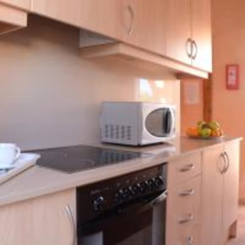 Cocina moderna en villa Las Golondrinas con microondas, estufa y paredes en tonos naranjas