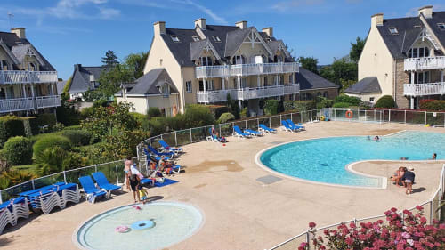 Outdoor pool and resort area at Location Vacances Finistère Sud in La Fôret-Fouesnant with sun loungers and seaside apartment
