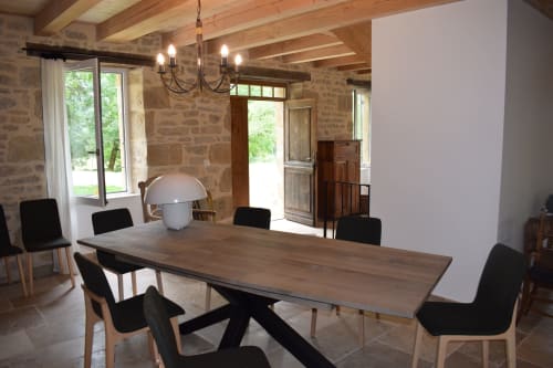 Salle à manger du gîte Les Pratges avec table en bois, chaises noires et murs en pierre à Figeac