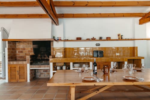 Cocina rústica con vigas de madera, chimenea de ladrillo y comedor en Las Golondrinas, Cap d'Artrutx