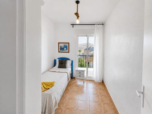 Bright bedroom in Apartamentos El Calón Playa with blue headboard, terracotta floor, sea view balcony, and modern amenities