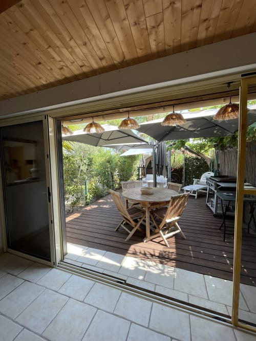 Terrasse spacieuse avec table à manger, chaises longues, parasols et vue sur le jardin de l'appartement La Montagnette à Cap d'Agde